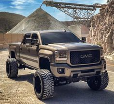 a silver truck parked in front of a large pile of dirt next to a mountain