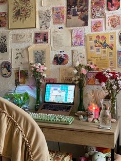 a laptop computer sitting on top of a wooden desk covered in pictures and pink flowers