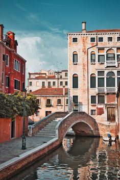 an old bridge over a small canal in the middle of a city with buildings on both sides