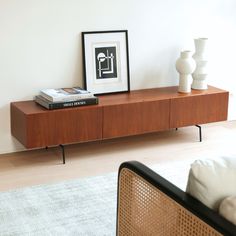 a wooden shelf with two vases and a book on it next to a white wall