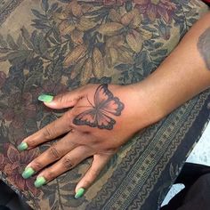 a woman's hand with a butterfly tattoo on it, resting on a cushion