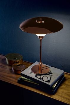 a lamp that is sitting on top of a book next to a pair of glasses