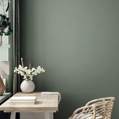 a chair and table in front of a mirror with plants on the wall next to it