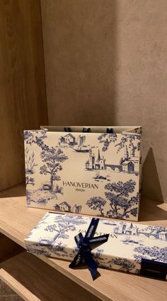 a blue and white gift bag sitting on top of a wooden shelf next to a box