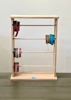 a wooden shelf with several spools of thread on it and two rolls of tape hanging from the top