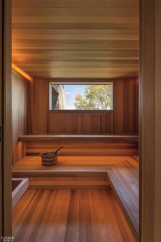 an empty sauna with wooden benches in the foreground and a window on the far wall