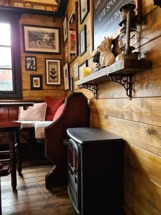 an old fashioned stove sits in the corner of a room with wood paneling and pictures on the wall