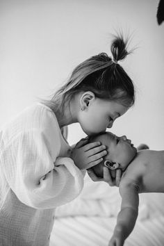 a black and white photo of a woman kissing a baby