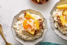 two bowls filled with food on top of a white table next to gold spoons