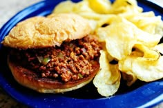 a blue plate topped with a sloppy joe and chips