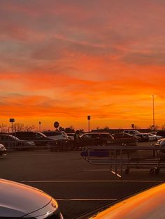 cars parked in a parking lot with the sun setting behind them and some clouds above