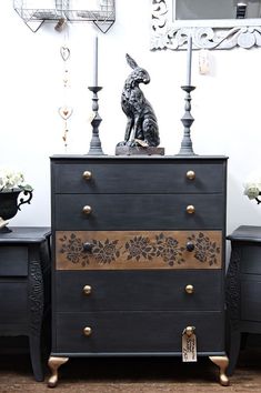 two black dressers with gold trim and decorative knobs on the handles, one has a rabbit statue on top