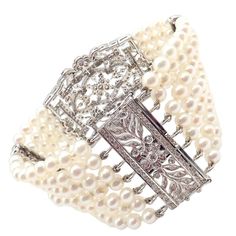 About This Piece: The Vintage Estate 18k White Gold Diamond 7 Row 4.5mm Pearl Bracelet features seven rows of lustrous 4.5mm pearls, intricately woven together. Each section is interspersed with delicate white gold bars studded with sparkling diamonds, enhancing the bracelet’s elegance and creating a luxurious, timeless accessory. Metal: 18k White Gold Stone: Diamonds: Approx 2.5ctw Pearls 174x White Pinkish High Luster 4.5mm Pearls Weight: 51.4g Width: 34mm Hallmarks: 750 3229medd Elegant Platinum Bracelets For Evening, Classic Diamond Pearl Bracelet For Formal Occasions, Classic White Gold Diamond Pearl Bracelet, Luxury White Diamond Pearl Bracelet, Luxury White Pearl Bracelet With Diamonds, Elegant Pearl Bracelet With Diamond Accents, Elegant White Gold Filigree Jewelry, Timeless Silver Pearl Jubilee Bracelet, Formal Diamond Pearl Bracelet With Jubilee Style