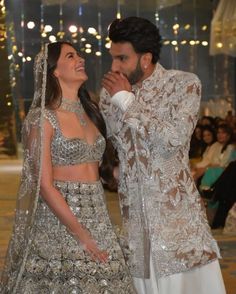 two people standing next to each other in front of a crowd at a fashion show