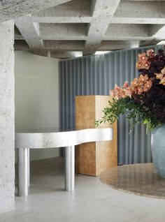 a vase filled with flowers sitting on top of a white table next to a wall