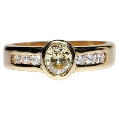 a yellow gold ring with white diamonds on the sides and a center stone in the middle