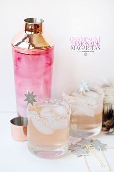 two glasses filled with pink liquid next to a copper shaker and star shaped straws