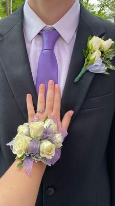 a man wearing a purple tie and matching wrist corsage with flowers on it