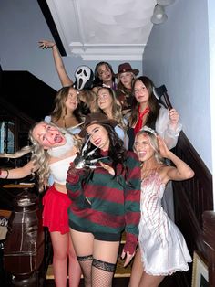 a group of young women dressed in costumes posing for a photo on the stairs at a halloween party