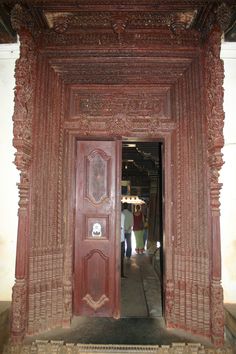 an ornate wooden door with carved carvings on the outside and inside, leading to another room