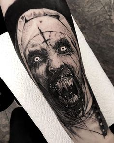 a man's arm with a scary face and cross tattoo on the upper half of his arm