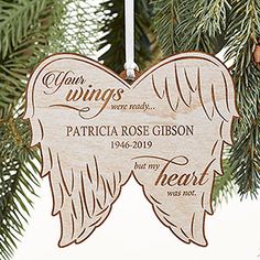 an ornament hanging from a christmas tree with pink angel wings on it's side