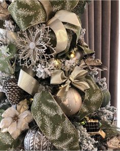 a christmas tree decorated with silver and gold ornaments, bows and snowflakes