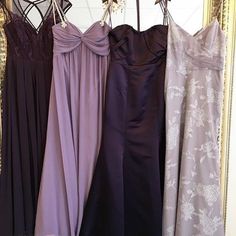 four bridesmaid dresses hanging in front of a mirror