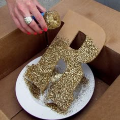 a person is cutting into a cake in the shape of the letter e with gold sprinkles