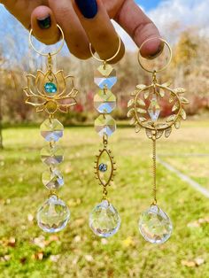 a person is holding three dangling earrings in their hand, with the sun and moon on them