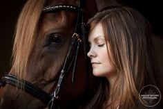 a beautiful young woman standing next to a brown horse