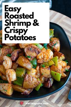 a black plate topped with shrimp and green peppers on top of a wooden table next to a fork