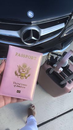 a person holding a pink passport in front of a car