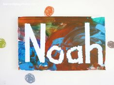 the word noah written in white paint on a piece of paper with buttons around it