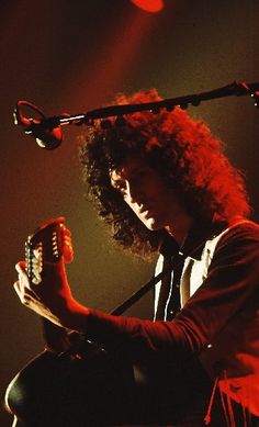 a man with long curly hair playing an instrument on stage at a music festival or concert