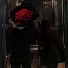 two people standing in front of an elevator with a large bouquet of flowers on their heads