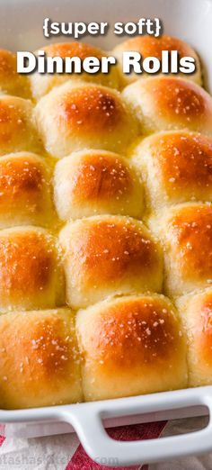 a white casserole dish filled with dinner rolls on a red and white cloth