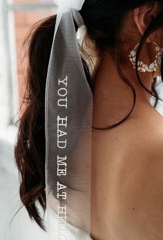 the back of a woman's head wearing a white ribbon with words on it