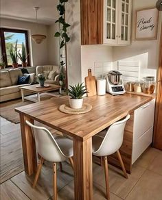 a wooden table sitting in the middle of a living room next to a kitchen area