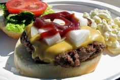 a hamburger with cheese and ketchup on a plate next to macaroni and cheese