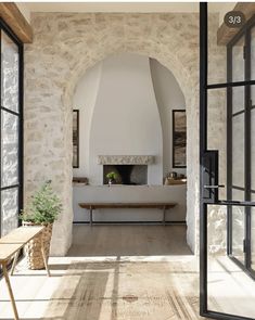 an arched doorway leads to a living room with stone walls and flooring, along with a bench in the center