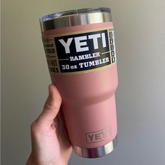 the yeti rambler tumbler is pink with gold trim and black lettering on it