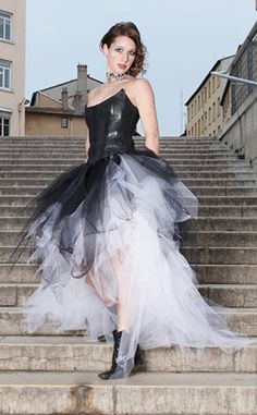 a woman in a black and white dress standing on some steps