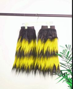 two pairs of yellow and black furry pants hanging from a clothes line with palm leaves