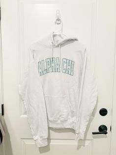 a white sweatshirt with the word alpaa chi on it hanging from a hook