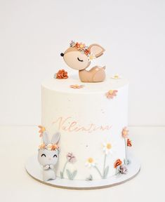 a white cake decorated with flowers and an animal figurine