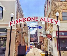 a fishbone alley sign on the side of a building in an alleyway between two buildings