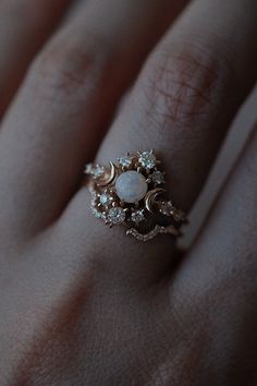 a woman's hand with a ring on it that has a white stone in the middle