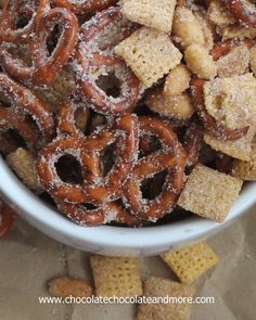 a white bowl filled with cheetos and pretzels next to crackers