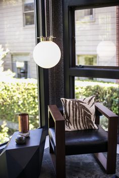 a living room with a chair, table and lamp on it's windowsill